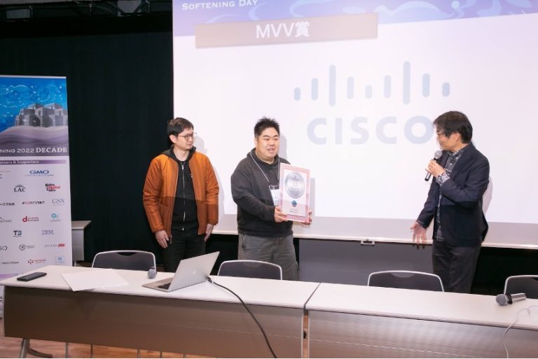 実行委員長から MVV 賞を驚きながら受けるシスコマーケットプレイスメンバー (Hardening Projectより提供)